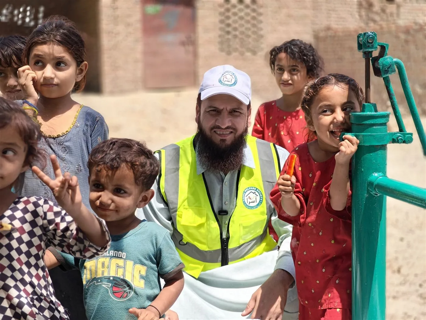 An Aasra volunteer with village children at a newly installed hand pump